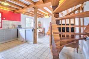 Una cocina equipada con microondas, lavavajillas y un comedor con mesa y sillas.