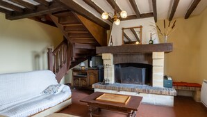 Un salón acogedor con chimenea, una escalera de madera y un sofá con cojines estampados.