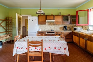 Une cuisine avec des meubles en bois, un pare-feu en carrelage, une table à manger avec des chaises et un luminaire suspendu.