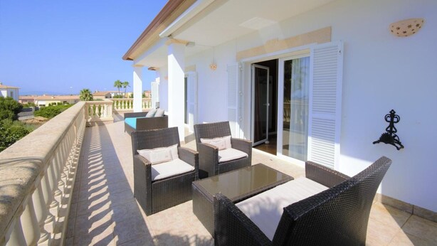 A balcony with wicker furniture, a glass table, and a view of the sea. - Villa 'Cunill' with Sea View, Wi-Fi and Air Conditioning (Llucmajor)