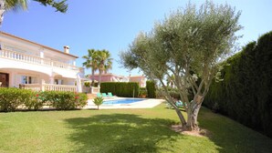 A house with a swimming pool, a well-maintained lawn, and a large tree. - Villa 'Cunill' with Sea View, Wi-Fi and Air Conditioning (Llucmajor)