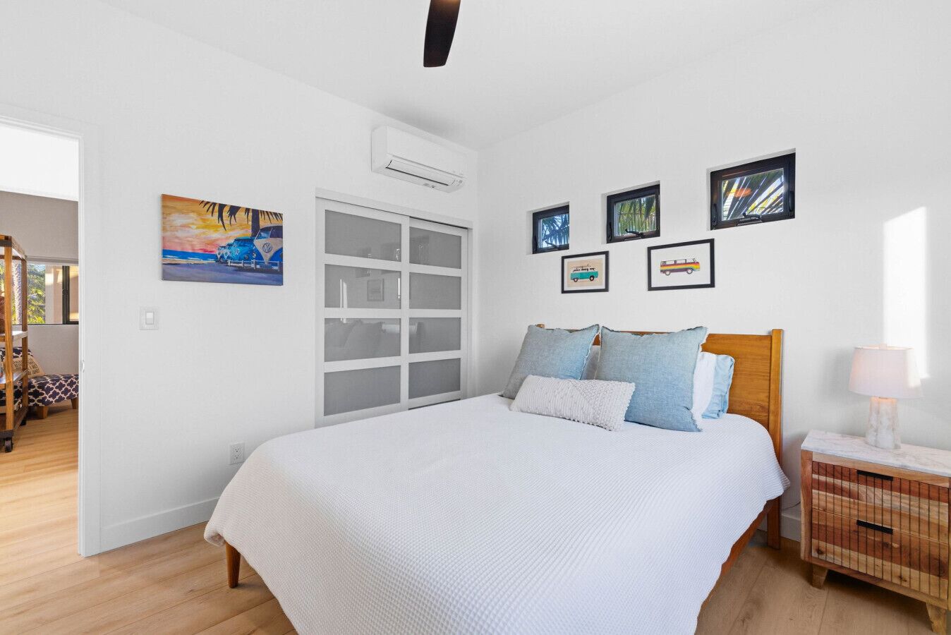 A bedroom with a bed, a nightstand, a window, and wall-mounted artwork.