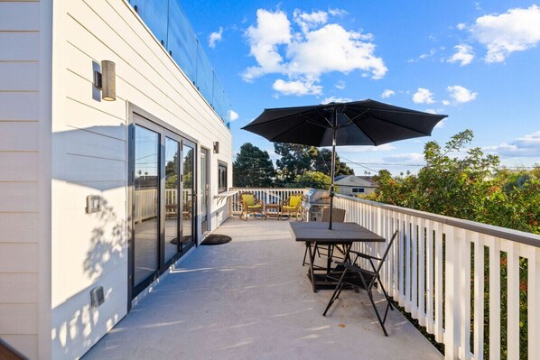 A balcony with a table, chairs, and an umbrella. - Brand New, Ocean/City Views, 2 Decks, AC, Parking! (San Diego)