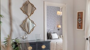 A hotel room with a bed, a dresser, a mirror, and a wall-mounted light fixture.