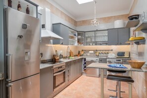 Een moderne keuken met roestvrijstalen apparatuur, grijze kastjes en een barkruk.