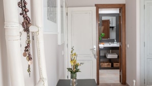 A hallway with a white door, a mirror, and a vase with flowers.