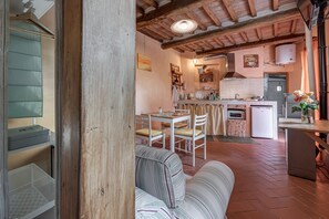 Une cuisine chaleureuse avec un coin repas, des poutres apparentes en bois au plafond et un sol carrelé.