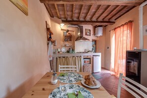 Une cuisine chaleureuse avec des poutres en bois, une table à manger avec des assiettes et un croissant, et un petit four.