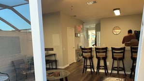 Une cuisine moderne avec un coin bar, des chaises en bois et une table à manger.