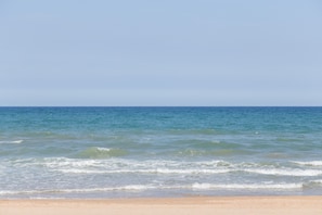 A beach with clear blue water and a sandy shore.