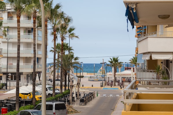 A coastal street with palm trees, a beach, and a hotel named 'HORCHATERI' in the background.