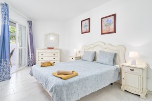 Une chambre à coucher avec un lit, des tables de chevet, une commode et une fenêtre avec des rideaux.