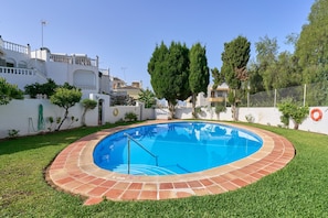 Une piscine bordée de briques, entourée d’une pelouse bien entretenue et d’arbres.
