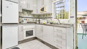 A kitchen with white cabinets, a microwave, a toaster, and a sink.