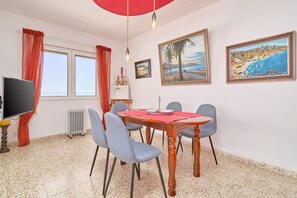 Un'area pranzo con un tavolo in legno, sedie blu, un ombrello rosso e opere d'arte alle pareti.