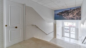 A staircase with a handrail, a white door, and a wall with a textured pattern.