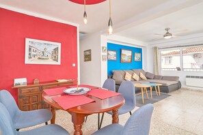 Un coin repas avec une table dressée pour quatre personnes, un canapé et un ventilateur de plafond.