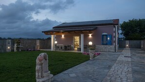 Une maison avec une façade en pierre, un patio couvert et une pelouse bien entretenue.