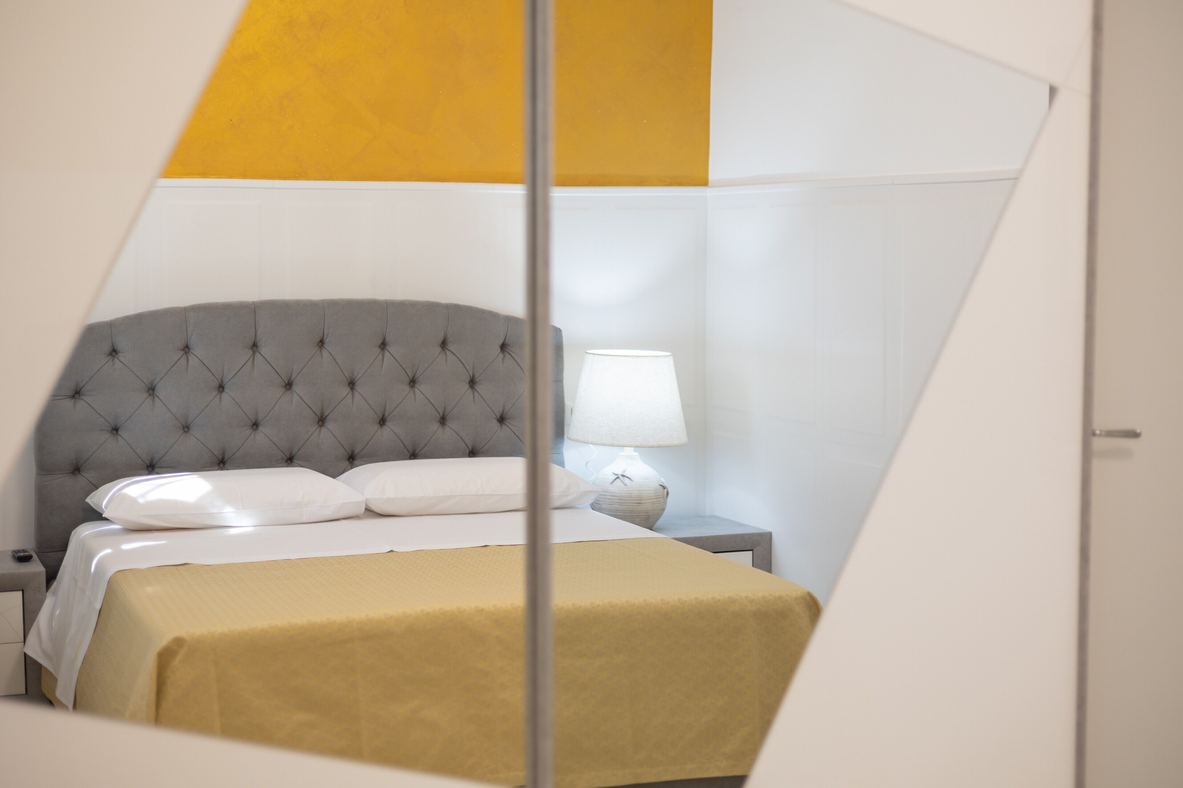 Un lit doté d’une tête de lit capitonnée, d’une lampe de chevet et d’une table de chevet.