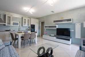 Una cocina moderna con comedor, un televisor de pantalla plana y una mesa de centro de vidrio.