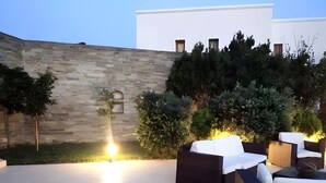 A patio with stone walls, outdoor furniture, and a well-lit area. - Country House 'Andros - Private Pool' with Sea View, Wi-Fi and Air Conditioning (Andros)