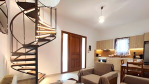 A compact living space with a spiral staircase, a kitchenette, a dining area, and a sofa. - Country House 'Andros - Private Pool' with Sea View, Wi-Fi and Air Conditioning (Andros)