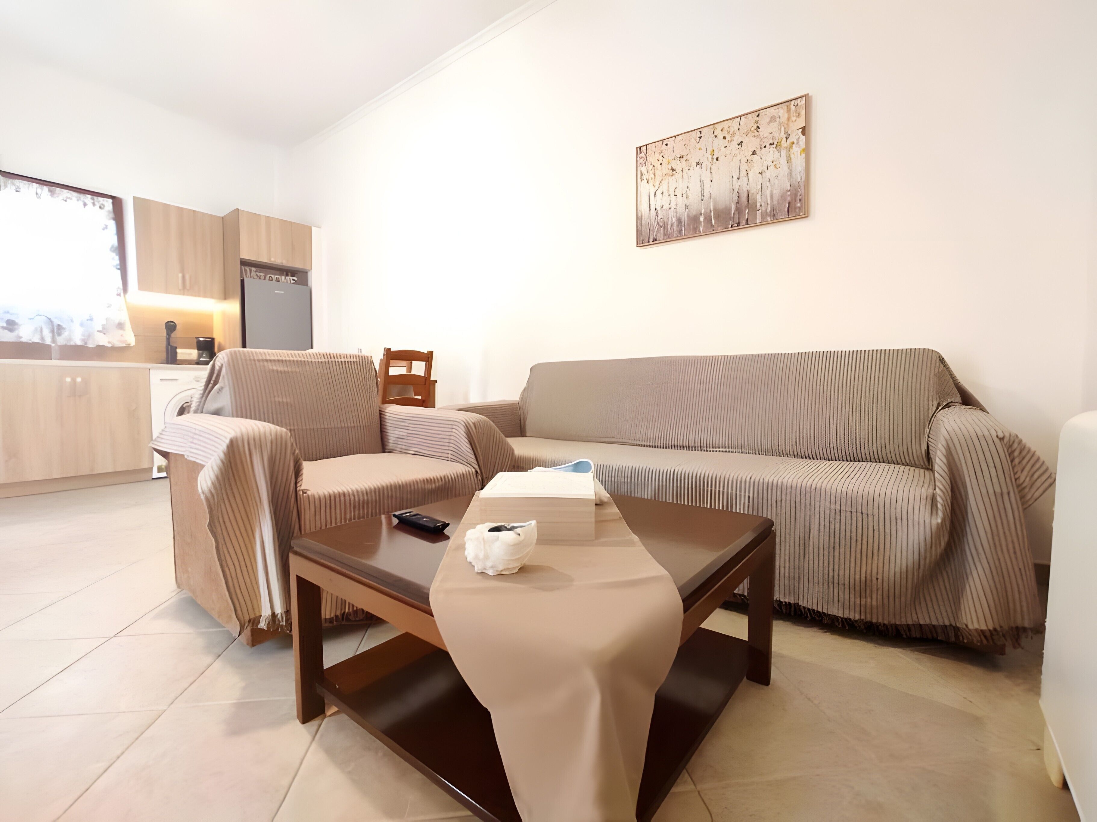 Una sala de estar moderna con un sofá, sillones, una mesa de centro y una cocina al fondo.