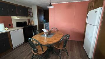 A compact kitchen with a dining table, chairs, and a refrigerator.