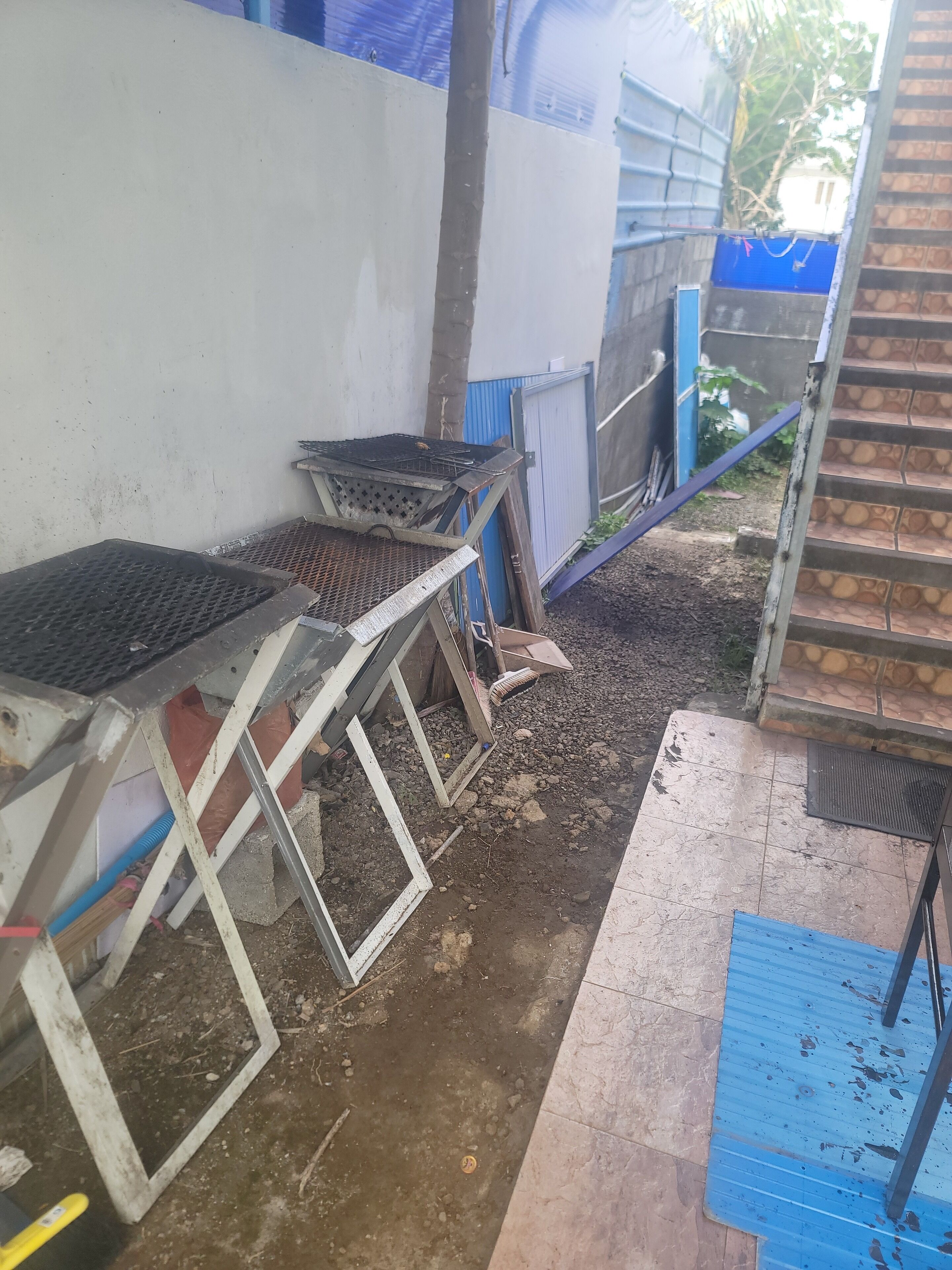 Un chantier de construction avec des structures métalliques, une porte bleue et un escalier.