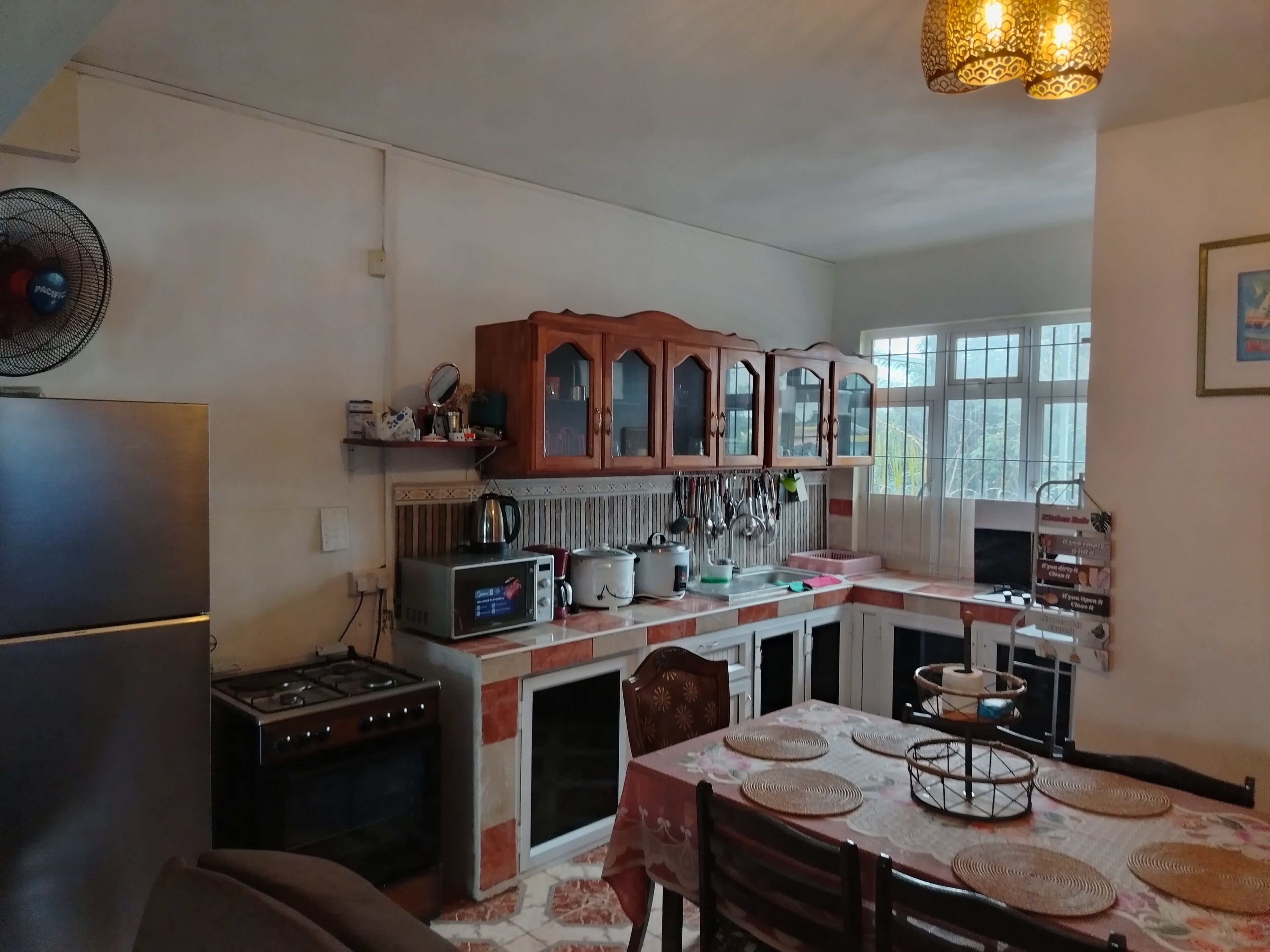 Une cuisine équipée d’un réfrigérateur, d’une cuisinière, d’un four à micro-ondes et de meubles de rangement en bois.