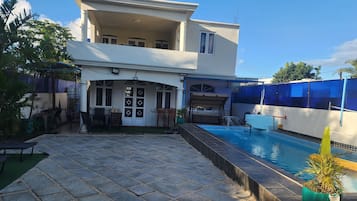 Un bâtiment à deux étages doté d’une piscine, d’un espace extérieur aménagé et d’une terrasse couverte.