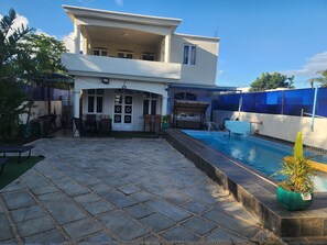 A two-story building with a swimming pool, outdoor seating area, and a covered patio. - Relax in budgey Villa with Jacuzzi and private Pool Perfect fr Groups & Families (Grand Baie)
