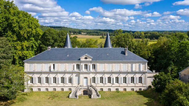A large, historic building with a symmetrical facade, a central entrance with a staircase, and two prominent conical structures on the roof. - The East Wing – Historic Elegance and Modern Comfort at Château de Mayac with Shared Pool (Mayac)