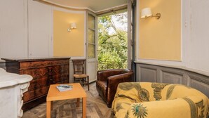 A room with a wooden dresser, a small table, a leather armchair, and a yellow armchair with a patterned throw. - The East Wing – Historic Elegance and Modern Comfort at Château de Mayac with Shared Pool (Mayac)