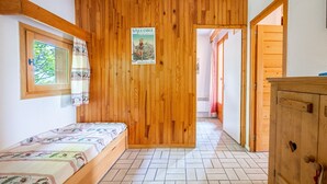 Ein Zimmer mit Holzwand, einem Bett mit gemustertem Überwurf, einem Poster an der Wand und einem Holzschrank.