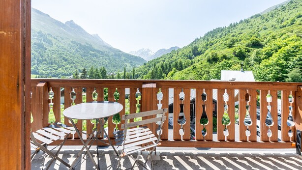 Ein Balkon mit Tisch und Stühlen, mit Blick auf eine Berglandschaft.