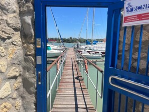 Une jetée en bois menant à une marina où sont amarrés des bateaux.