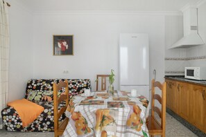 A compact kitchen with a microwave, a refrigerator, and a dining area with a table set for two.