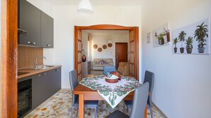 A compact kitchen with modern appliances, a dining area with a table set for two, and a living space with a sofa and decorative wall art. - Casa Merlino - Triple Room with Balcony (Santo Spirito)