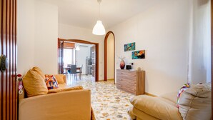 A living room with a sofa, a coffee table, a wooden cabinet, and a painting on the wall. - Casa Merlino - Triple Room with Balcony (Santo Spirito)