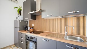 A modern kitchen with a built-in oven, a microwave, a sink, and a wooden backsplash. - Casa Merlino - Triple Room with Balcony (Santo Spirito)