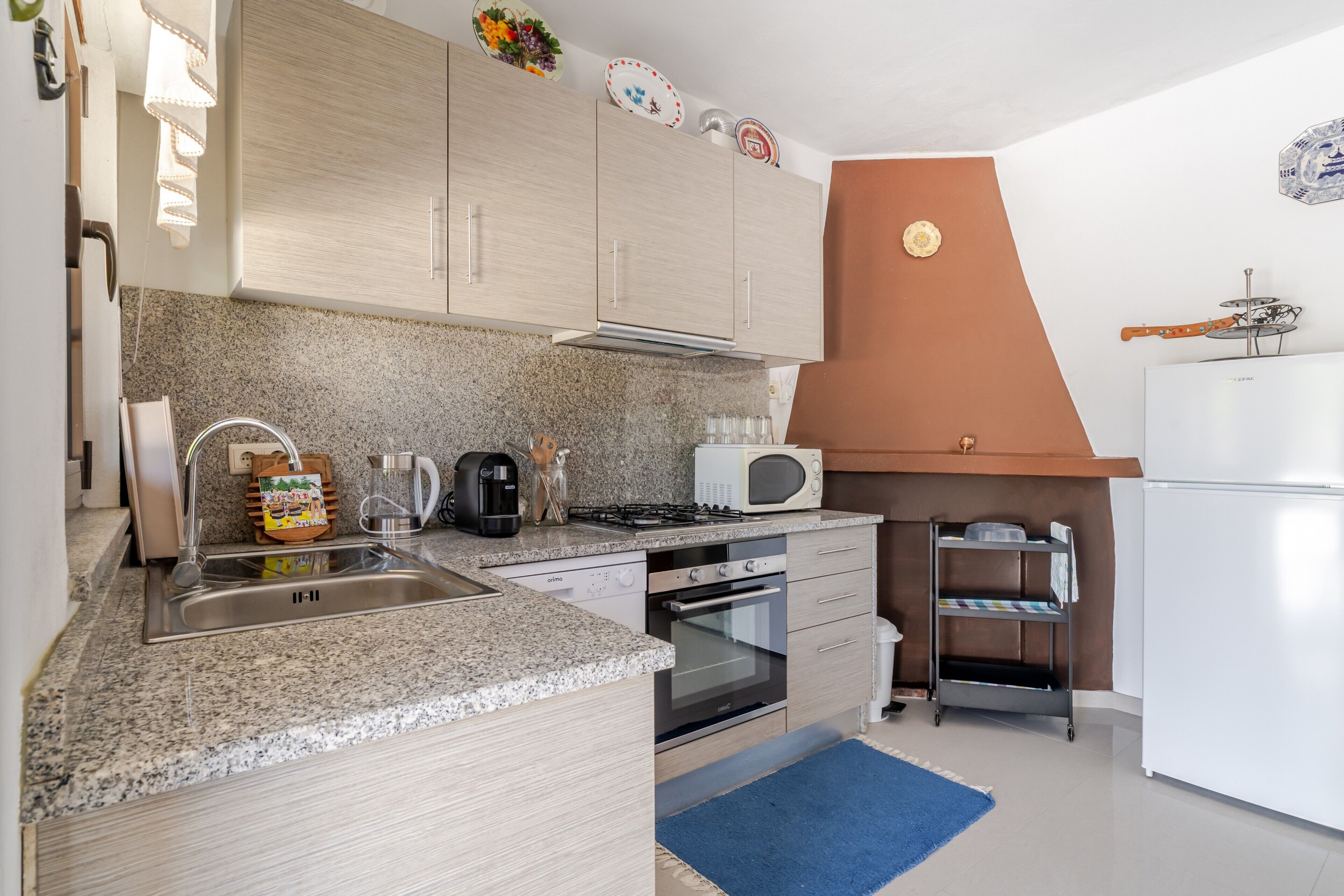 A compact kitchen with granite countertops, a built-in oven, a microwave, and a gas stove.