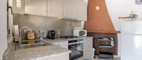 A compact kitchen with granite countertops, a built-in oven, a microwave, and a gas stove.