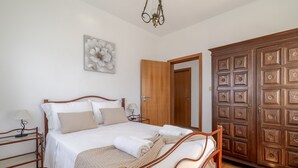 A bedroom with a wooden bed frame, a large wardrobe, and a wall-mounted artwork. - Superior Apartment with Mountain View, Shared Garden, and Wi-Fi Access (Ponte da Barca)