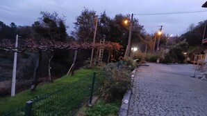 A cobblestone pathway leading to a building with a green fence and trees in the background. - Superior Apartment with Mountain View, Shared Garden, and Wi-Fi Access (Ponte da Barca)