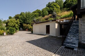 Une allée pavée menant à un bâtiment doté d’un escalier en pierre et d’une rampe en métal.