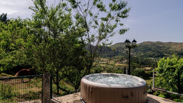 A hot tub surrounded by greenery and hills. - Superior Apartment with Mountain View, Shared Garden, and Wi-Fi Access (Ponte da Barca)