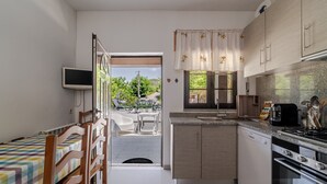 A compact kitchen with a dining area, a TV mounted on the wall, and a view of the outside. - Superior Apartment with Mountain View, Shared Garden, and Wi-Fi Access (Ponte da Barca)