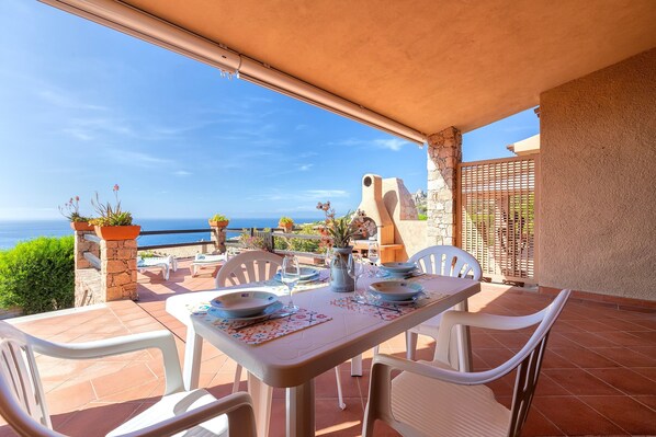An outdoor patio with a table set for dining, chairs, and potted plants.