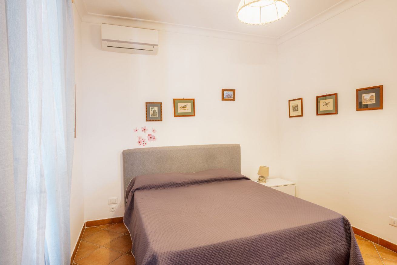 A bedroom with a bed, a nightstand, a lamp, and framed pictures on the wall.